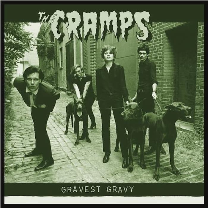 The Cramps 'Gravest Gravey' album cover, featuring the band members and their dogs in a sepia-toned outdoor alleyway.