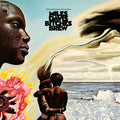 Album cover of 'Bitches Brew' by Miles Davis featuring a stylized portrait, floral elements, and a beach scene.