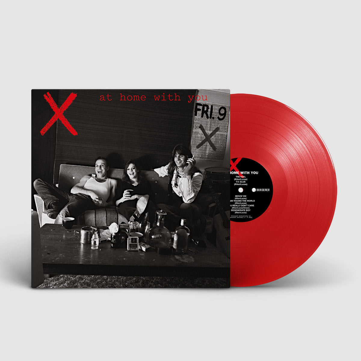 Red vinyl record with black and white cover showing people on a couch, on a light gray background.
